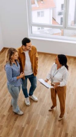 High angle view of real estate agent talking with young couple at empty apartment