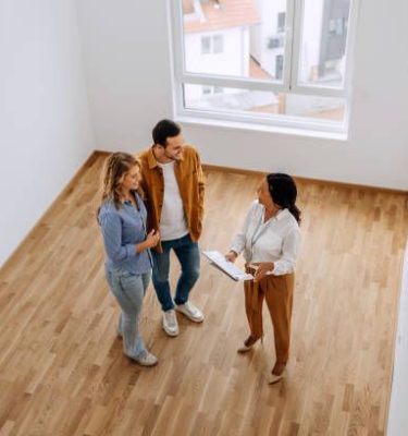 High angle view of real estate agent talking with young couple at empty apartment
